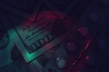 Haplar, uyuşturucular ve dolar nakit para. Tasarım için karanlık bir arka plan modeli olan neon ışığı altında bir paket.