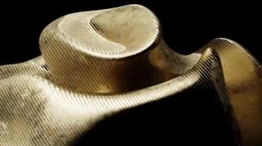 Soyut bir altın heykelin yakın çekimi pürüzsüz, dalgalı kıvrımlar ve dokular sergiliyor..