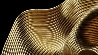 Akan çizgiler ve kıvrımların yer aldığı soyut bir altın heykelin yakın çekimi.