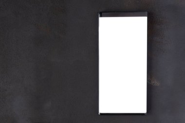 Siyah desenli masa arkaplanı üzerinde boş ekran modeli olan cep telefonu. Akıllı telefon ekranına çeşitli içerikler yerleştirmek için bir model. Üst görünüm, düz görünüm.