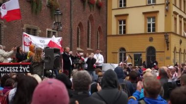 Wroclaw, Polonya - 10 Ekim 2020 - Sahte salgına karşı büyük barışçıl protesto. İnsanlar kalabalığın önünde mikrofonla konuşuyor. Polonya 'nın kırmızı-beyaz bayrakları arasında.