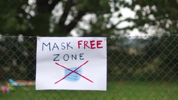 Poster sulla recinzione con l'iscrizione Mask Free Zone. Usato maschere protettive chirurgiche appendere nelle vicinanze. Protesta contro indossare maschere, Concetto anti-maschera — Video Stock