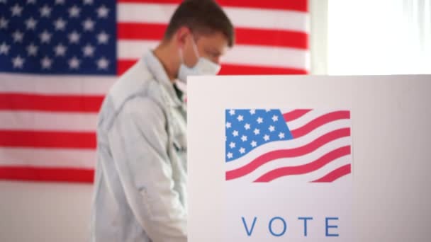 Muž v lékařské masce ukazující, že jsem hlasoval e-mailovou nálepkou s vlajkou USA jako pozadí - koncepce pošty při volbách do USA. Gesto palce nahoru — Stock video