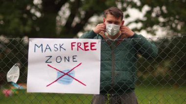 Bölge maske takmaktan muaf. Maskeler, şüpheciler ve onların protestoları. Çitteki poster. Genç adam maskeyi çite astı ve gitti.