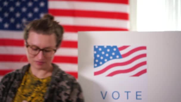 Frau in medizinischer Maske, die zeigt, dass ich per Postaufkleber mit US-Flagge als Hintergrund gewählt habe. Konzept der Weiblichkeit bei der Stimmabgabe bei US-Wahl — Stockvideo