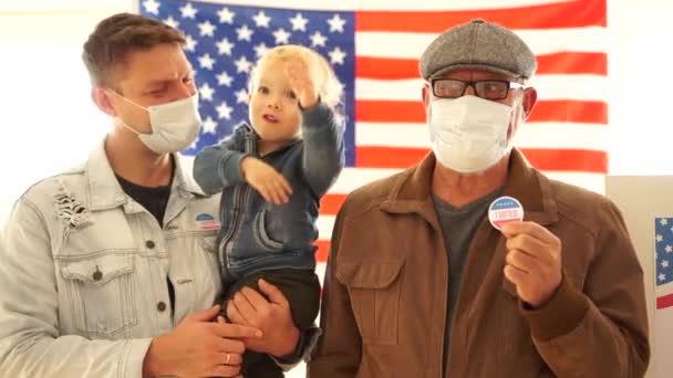 Pai, filho e neto têm autocolantes de voto. Os homens usam máscaras protectoras, nós eleições durante a epidemia do covid-19. Três gerações da família americana vieram votar na estação de votação — Vídeo de Stock