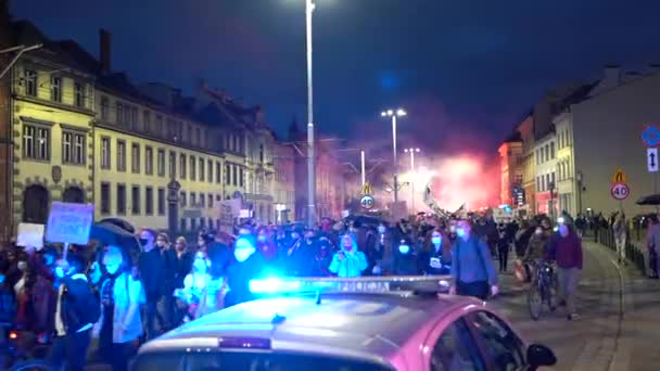 Wroclaw, Lengyelország, 2020. október 26. - Lengyel nők sztrájkja. Egy álarcos tömeg lengyelül zászlókkal háború. Van egy rendőrautó villogó fényekkel az út szélén. — Stock videók