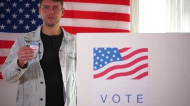 Oy merkezindeki genç Amerikalı 'nın elinde benim oyum olan bir çıkartma var. Adam kot ceket giyiyordu. ABD seçim kavramı