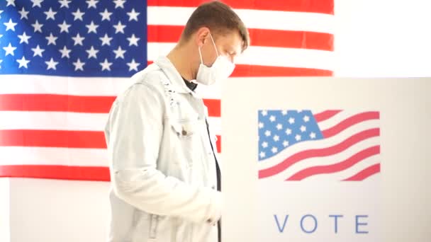Egy álarcos férfi szavaz egy szavazóhelyiségben az Egyesült Államokban. Covid-19 és az amerikai választások 2020-ig — Stock videók