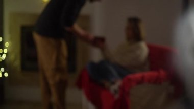 Sıcak ve sıcak ev kıyafetleri içinde sevgi dolu mutlu bir çift süslü bir Noel ağacının arka planında birbirlerine ve sıcacık bir evde şömineye bakar. Kız ve erkek aşık.