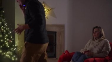 Bir çift şöminenin yanında rahat bir evde oturuyor. Adam odada yürüyor ve gergin bir şekilde konuşuyor, kadın ona endişeyle bakıyor. Aile sorunları kavramı, mali sorunlar ve noel
