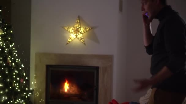 Familieproblemen concept, financiële problemen en kerst. Er zitten er een paar bij de open haard in een gezellig huis. De man loopt rond en praat zenuwachtig, de vrouw kijkt angstig naar hem — Stockvideo