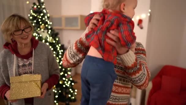 La nonna e il nonno sono venuti a trovare il nipote con dei regali. Buona famiglia e buon Natale. Bambino bambino saluta suo nonno — Video Stock