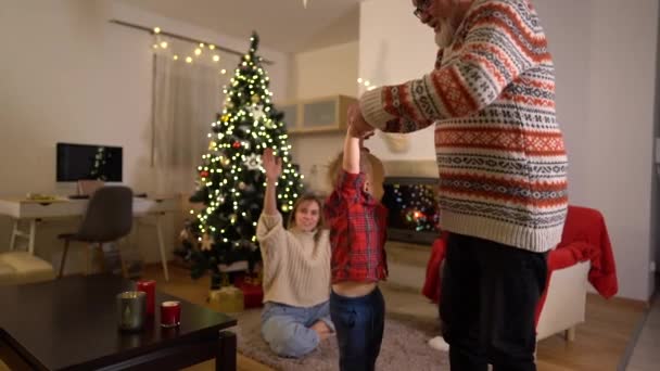 Дідусь танцює зі своїм онуком біля ялинки. Щаслива родина святкує Різдво біля каміна — стокове відео