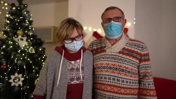 Glad familj möter jul covid-19 pandemi. Gammal par bär skyddande medicinska masker. Karantänisolering socialt avstånd. Nytt år semester. Festligt humör 2021 under nedstängning — Stockvideo