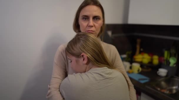 Madre e hija, víctimas de violencia doméstica se están abrazando en la cocina. La cara de las mujeres muestra moretones y abrasiones. Detener la violencia doméstica y el abuso — Vídeo de stock