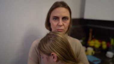 Aile içi şiddeti ve istismarı durdurun. Anne ve kızı, aile içi şiddet mağdurları mutfakta birbirlerine sarılıyorlar. Kadının yüzünde çürükler ve sıyrıklar var.