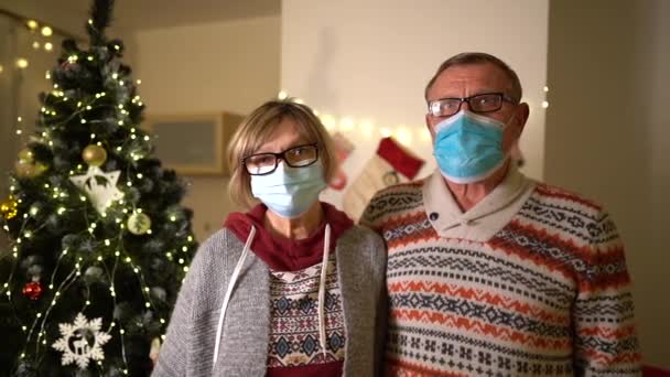 La famiglia felice incontra la pandemia di Natale Covid-19. Coppia matura con maschere mediche protettive. Separazione dalla quarantena distanza sociale. Vacanza di anno nuovo. Modo festivo 2021durante il blocco — Video Stock