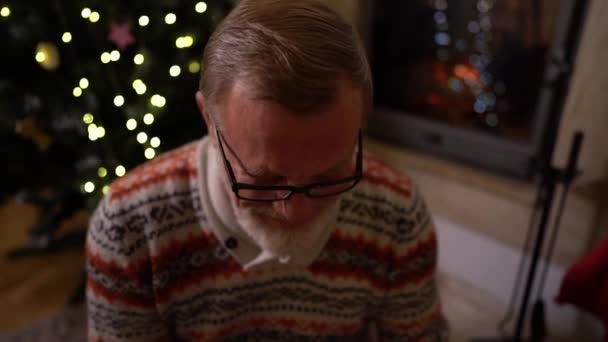 Elderly man, his wife and adult daughter on Christmas evening. A friendly family celebrates Christmas by the fireplace. Christmas tree in home interior — Stock Video