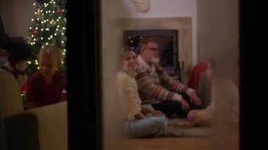 Mutlu bir aile, yaşlı bir çift, kızları ve küçük torunları ve bir köpek Noel akşamı şöminenin yanında eğleniyorlar. Aile Noel 'i kutluyor, pencereden buzla bakıyor.