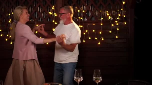 Mature man dancing with a woman at a family party. Wedding anniversary or birthday celebration in a restaurant. Dancing in the background of lights — Vídeo de Stock