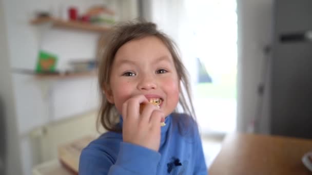 귀여운 소녀가 집에서 만든 쿠키를 먹으면서 부엌에서 맛있는 요리를 즐기고 있습니다. 행복 한 유년 시절, 성탄절 생강 — 비디오