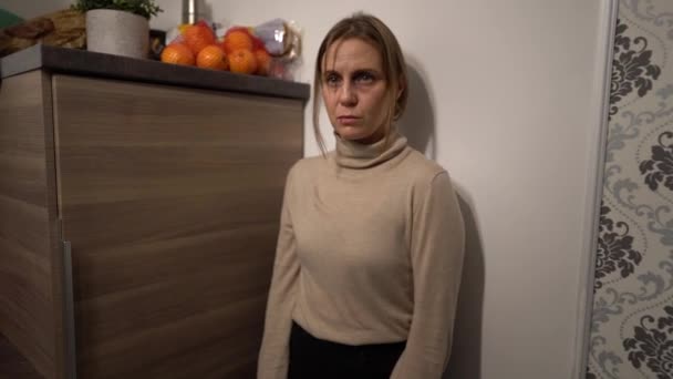Φοβισμένη νοικοκυρά στην κουζίνα. Στενή προσωπογραφία μιας κακοποιημένης γυναίκας με μαυρισμένο μάτι και σχισμένο χείλος. Σταματήστε την ενδοοικογενειακή βία και τον αλκοολισμό — Αρχείο Βίντεο