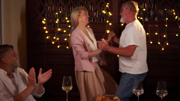 Mature man dancing with a woman at a family party. Wedding anniversary or birthday celebration in a restaurant. Dancing in the background of lights — Vídeo de Stock