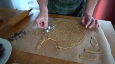 Yaşlı bir kadının el yapımı kurabiyeleri yağsız kağıttaki metal kalıpla yaparken yakın plan fotoğrafı. Noel kurabiyesi, ev yapımı kurabiyeler.