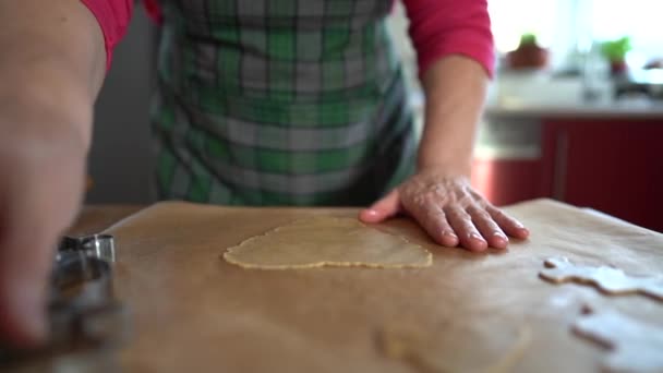 Domácí recept na sušenky, tradiční vaření. Zralý kuchař dělá sušenky z těsta pomocí kovové formy. Těsto leží na nepromastitelném papíru. Domácí recept na sušenky, tradiční vaření — Stock video