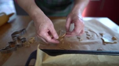 Emekli, çiğ kurabiyeleri bir yemek tepsisinin üzerine serer. Ev yapımı gelenekler. Noel kurabiyeleri. Kadın fırıncının elleri tepside kurabiye, zencefilli ekmek tarifi gösteriyor.