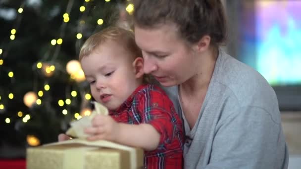 ママと小さな息子がクリスマスプレゼントを開いている。新年やクリスマスのお祝い、幸せな家族、サンタクラスからの贈り物 — ストック動画