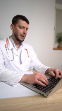 Teletıp konsepti - erkek aile doktorunun dikey hali dizüstü bilgisayarla hastayla konuşuyor ve notlar yazıyor. Pulmonolog danışmanlık yapıyor, yeni normallik...