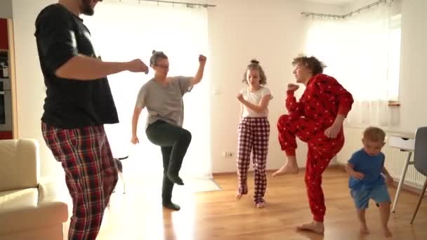 Happy family is doing gymnastics in pajamas at home on the floor. Stay at home concept, kids leisure during lockdown coronavirus covid-19, parents and kids — Stock Video