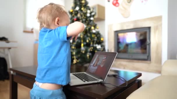 Tout-petit danse à côté d'un ordinateur portable lors d'un appel vidéo à ses grands-parents. Les grands-parents souhaitent au petit-fils Joyeux Noël et Bonne Année via un lien vidéo. Nouveau concept normal, rester à la maison — Video