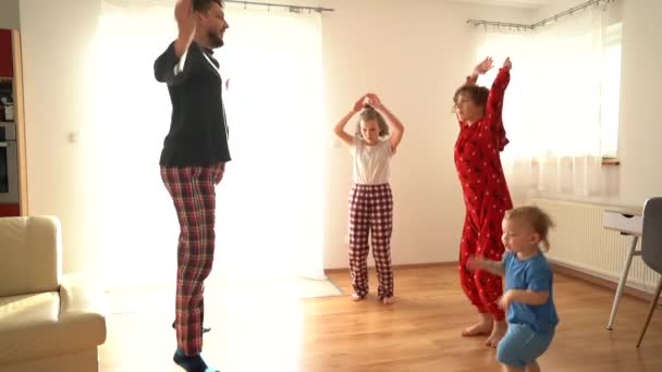 Ευτυχισμένος πατέρας και τρία παιδιά κάνουν γυμναστική στο σπίτι. Η οικογένεια είναι ντυμένη με πιτζάμες. Ημέρα πατέρων — Αρχείο Βίντεο