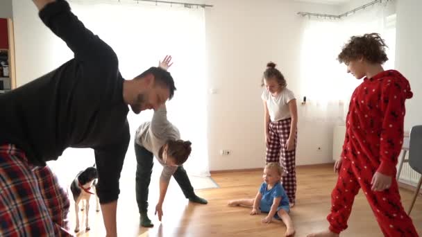 Manželka a tři děti, šťastná rodina, legrační video. Velká rodina se třemi dětmi, které dělají ranní cvičení v pyžamu. K popukání, zůstaň doma. — Stock video