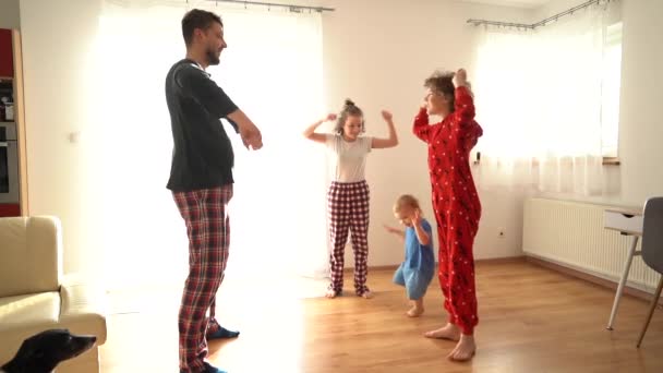 Большая семья с тремя детьми, занимающимися утренними упражнениями в пижаме. Уморительная изоляция, оставайся дома, день отцов — стоковое видео