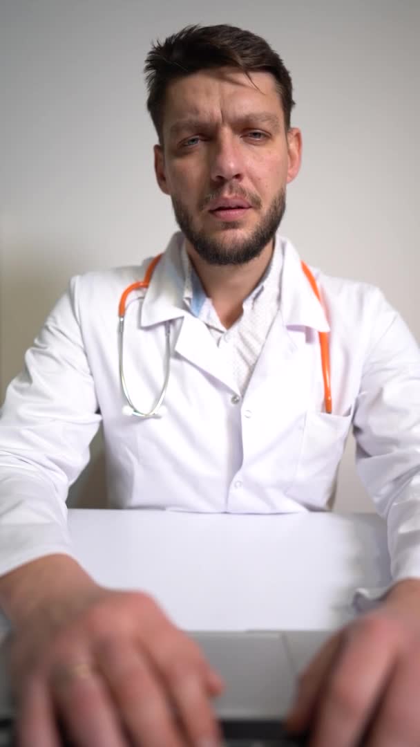 VIDÉO VERTICALE du médecin de famille masculin parle au patient par webcam portable et écrit des notes. Pulmonologue consulte en ligne, la nouvelle normalité, concept de télémédecine — Video