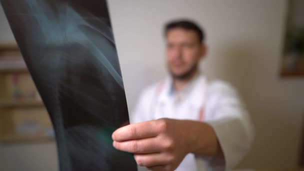 An experienced doctor looking at x-rays of the patients lungs. Close-up x-ray picture of the patient in the hand of the doctor. A patient with pneumonia, staging a diangosis coronavirus covid-19 — Stock Video