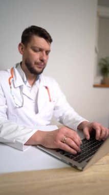 Dikey video. Genç bir erkek doktor bir hastayla çevrimiçi istişarede bulunuyor. Tele tıp konsepti, aile doktoru.