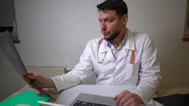 Porträtt av den trötta doktorn gäspar lägger röntgen åt sidan och gnider hans ögon. Professionell utbrändhet, medicinsk kollaps koncept — Stockvideo