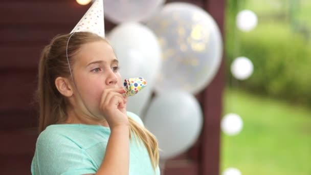 Porträt eines Mädchens mit Partyhorn, das in Blasinstrumente bläst. Herzlichen Glückwunsch zum Geburtstag, Porträt auf Luftballons, Kindergeburtstag — Stockvideo