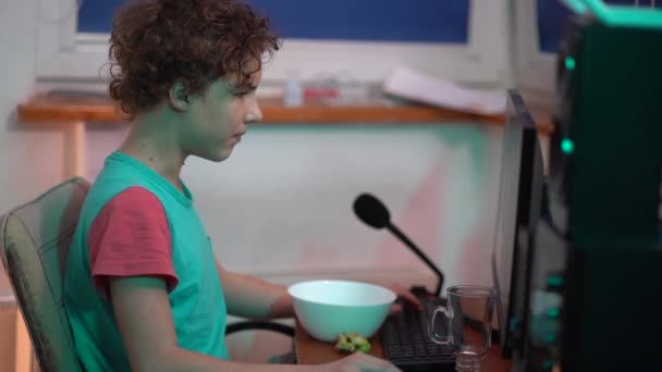 Mladý chlapec s herními sluchátky vypadá frustrovaný z monitoru. Video Gamer hraje videohru. Šprt, co hraje online. Problémové dospívající — Stock video