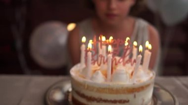 Doğum günü kızı büyük, lezzetli doğum günü pastasına mum üflüyor. Küçük şirin kızların doğum günü. Bir çocuk doğum gününde dilek tutar. Karantina ve kendini izole etme