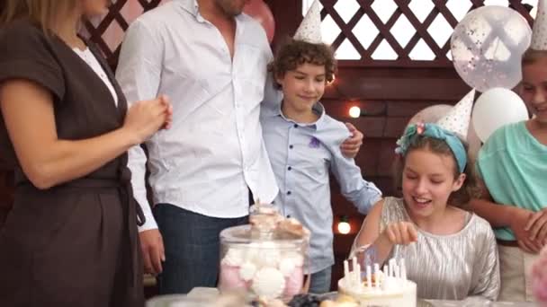 Wesoła solenizantka licząca świeczki na torcie urodzinowym. Rodzina gratuluje córce, dzieci na świeżym powietrzu urodziny, koncepcja cateringu — Wideo stockowe