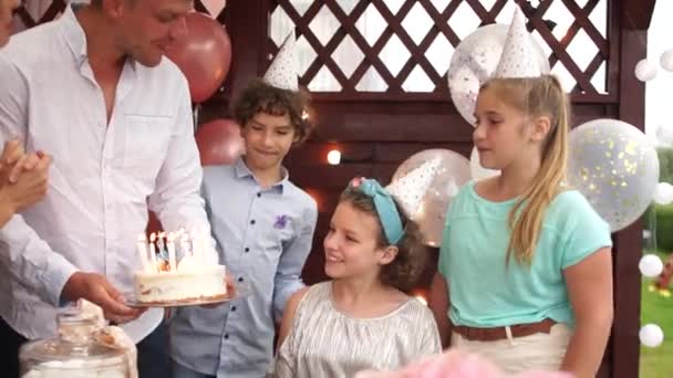 La famiglia felice festeggia il compleanno di un'adolescente. Genitori e amici baciano e abbracciano la festeggiata. Torta di compleanno e candele — Video Stock