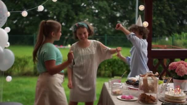 Słodkie nastolatki tańczą na przyjęciu urodzinowym przy stole. Uczniowie mają zabawne, szczęśliwe dzieciństwo — Wideo stockowe
