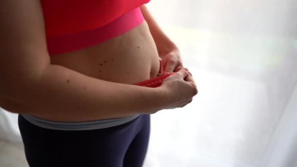 Närbild ung kvinna mäter hennes midja med ett måttband. Flickan är missnöjd med sin figur, postpartum depression — Stockvideo