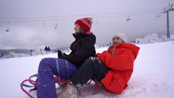 Chicas adolescentes felices deslizándose por la colina en trineo. Chica enyoing deslizador paseo en la nieve. Feliz infancia, pista de esquí — Vídeo de stock